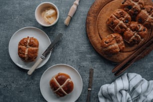 a plate of hot cross buns next to a bowl of butter
