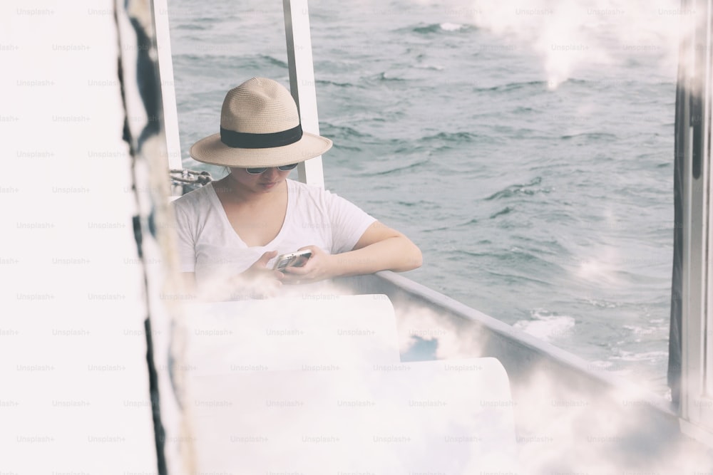 Eine Frau, die auf einem Boot sitzt und auf ihr Handy schaut