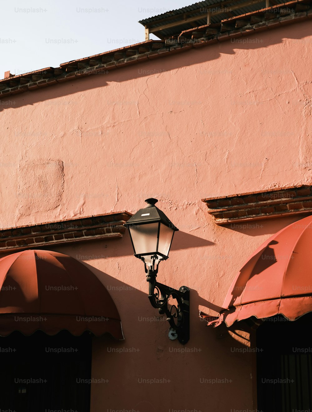 Una lámpara en el costado de un edificio rosa