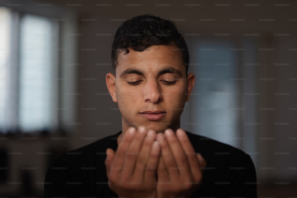 a young man is praying in a dark room