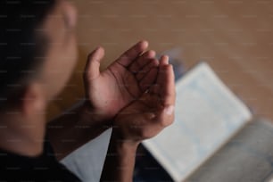 une personne tenant ses mains jointes devant un livre