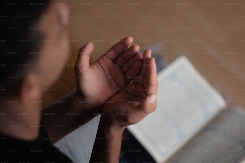 uma pessoa segurando as mãos juntas na frente de um livro