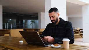 a man sitting at a table using a laptop computer