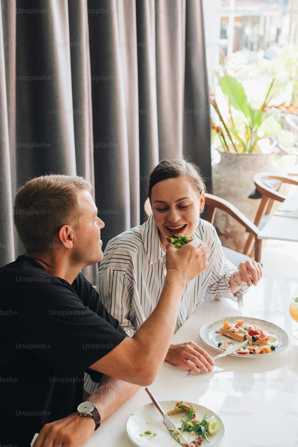 un uomo e una donna seduti a un tavolo che mangiano cibo