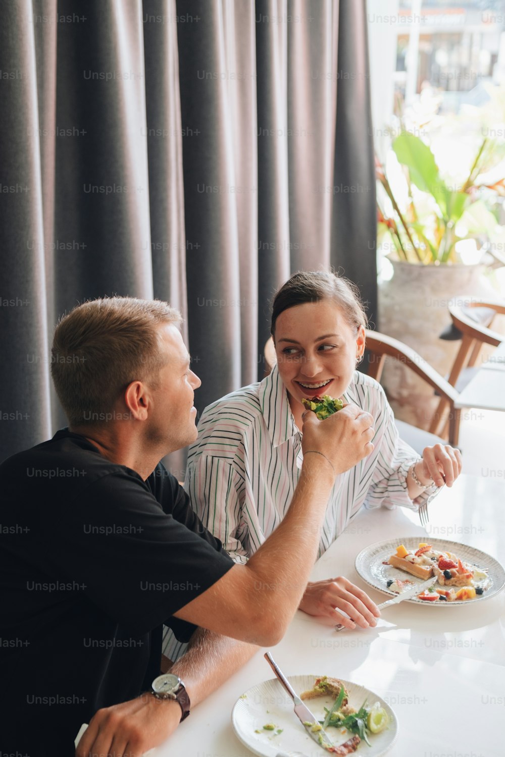 a man and a woman sitting at a table eating food