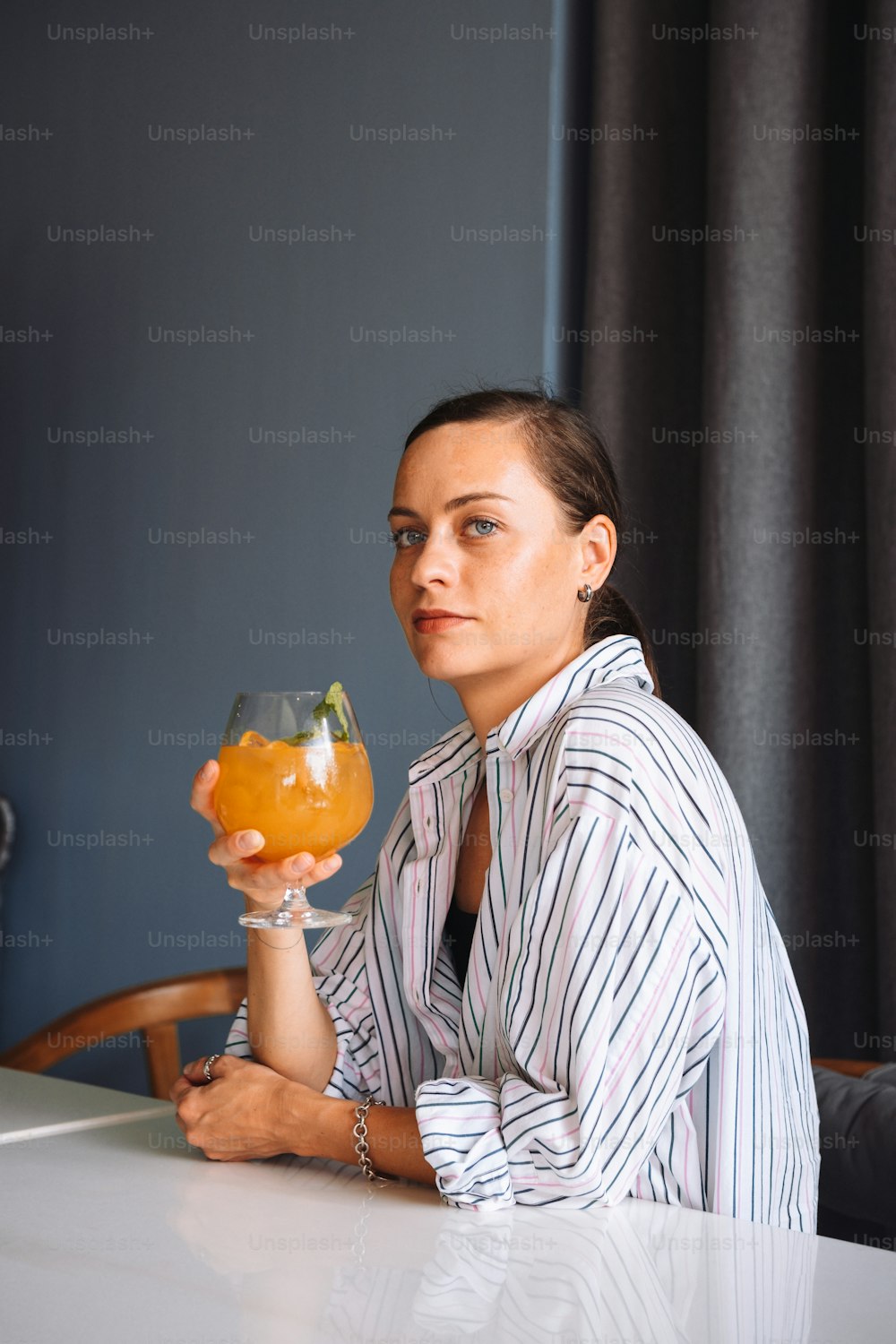 a woman sitting at a table holding a glass of orange juice