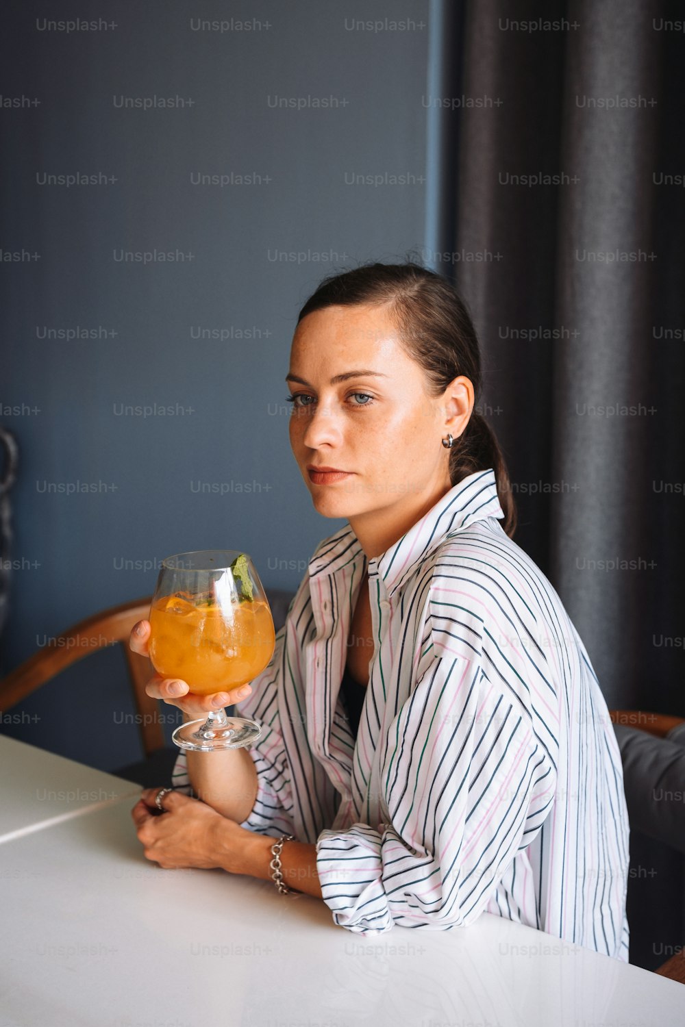a woman sitting at a table holding a drink