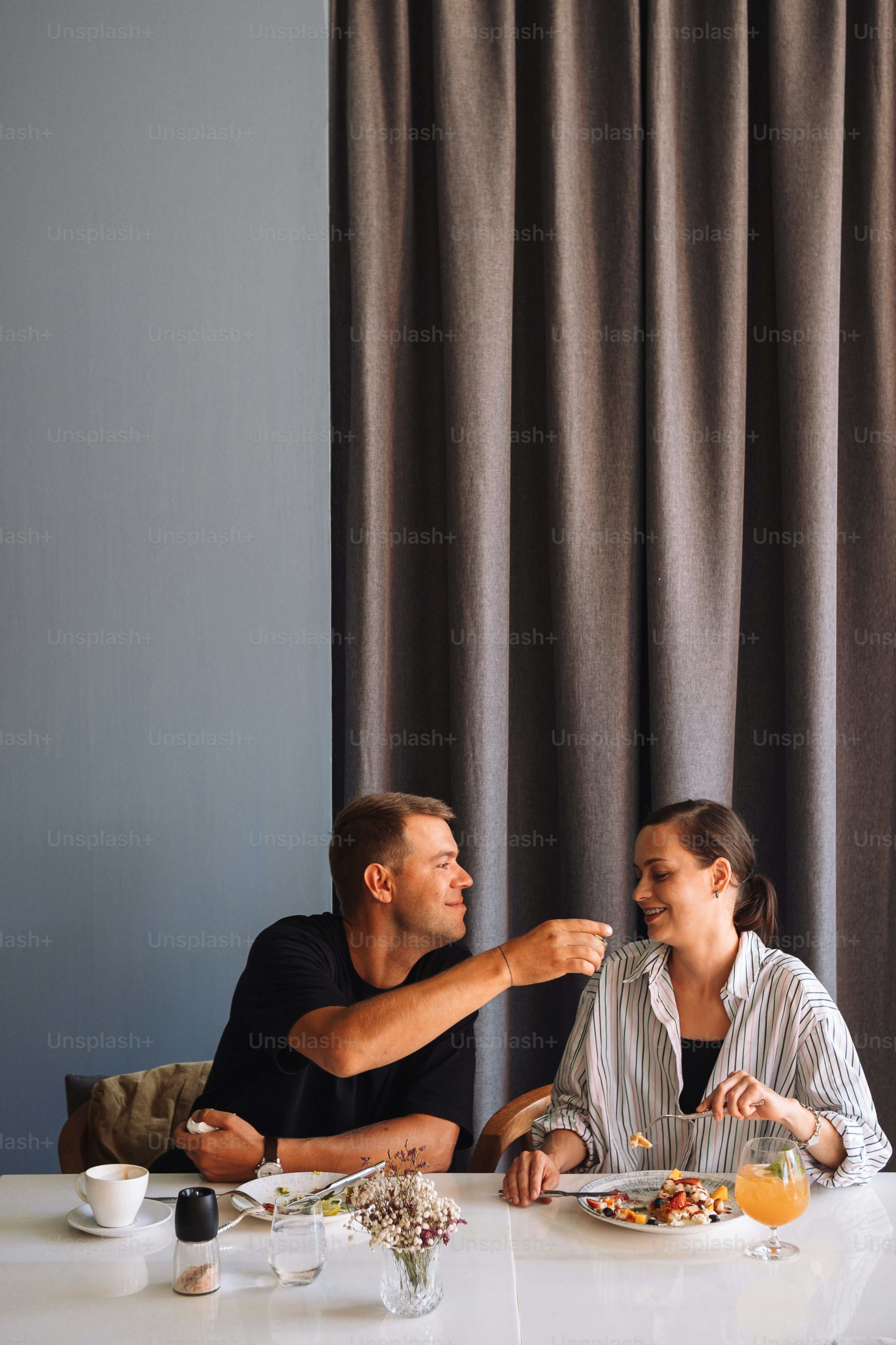 a man and woman sitting at a table with food