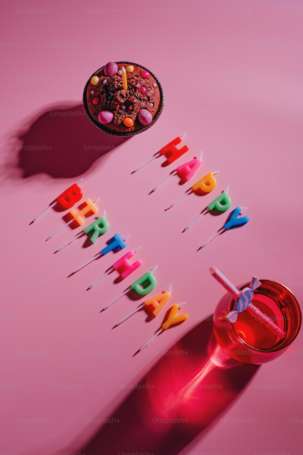 Un pastel de cumpleaños con velas en una mesa rosa