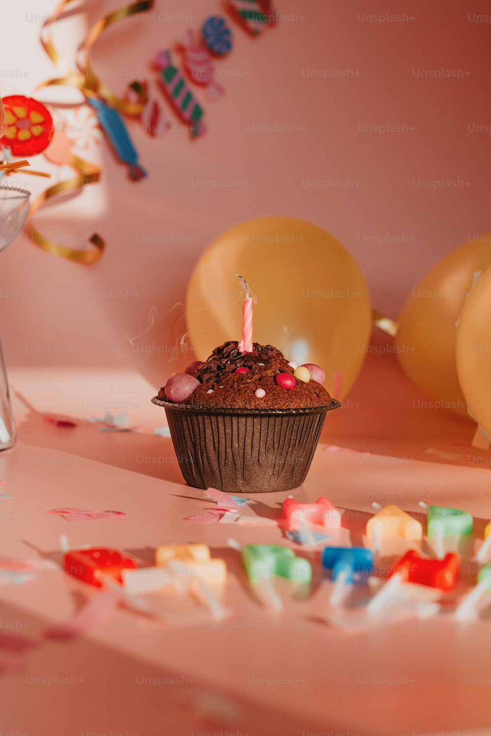 um cupcake sentado em cima de uma mesa ao lado de balões