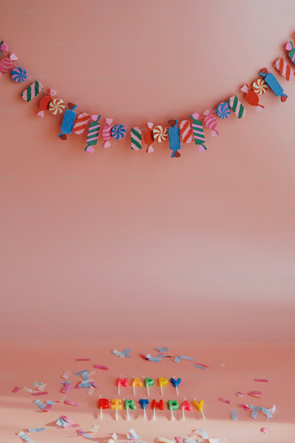 eine Geburtstagstorte mit Kerzen und Luftschlangen auf rosa Hintergrund
