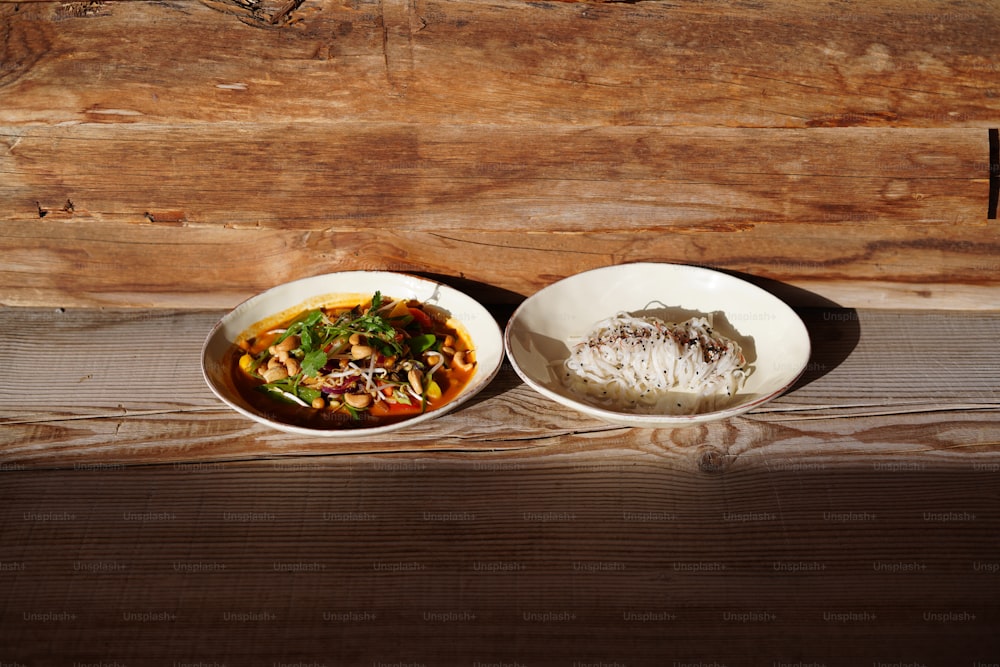 two bowls of food sitting on a wooden table
