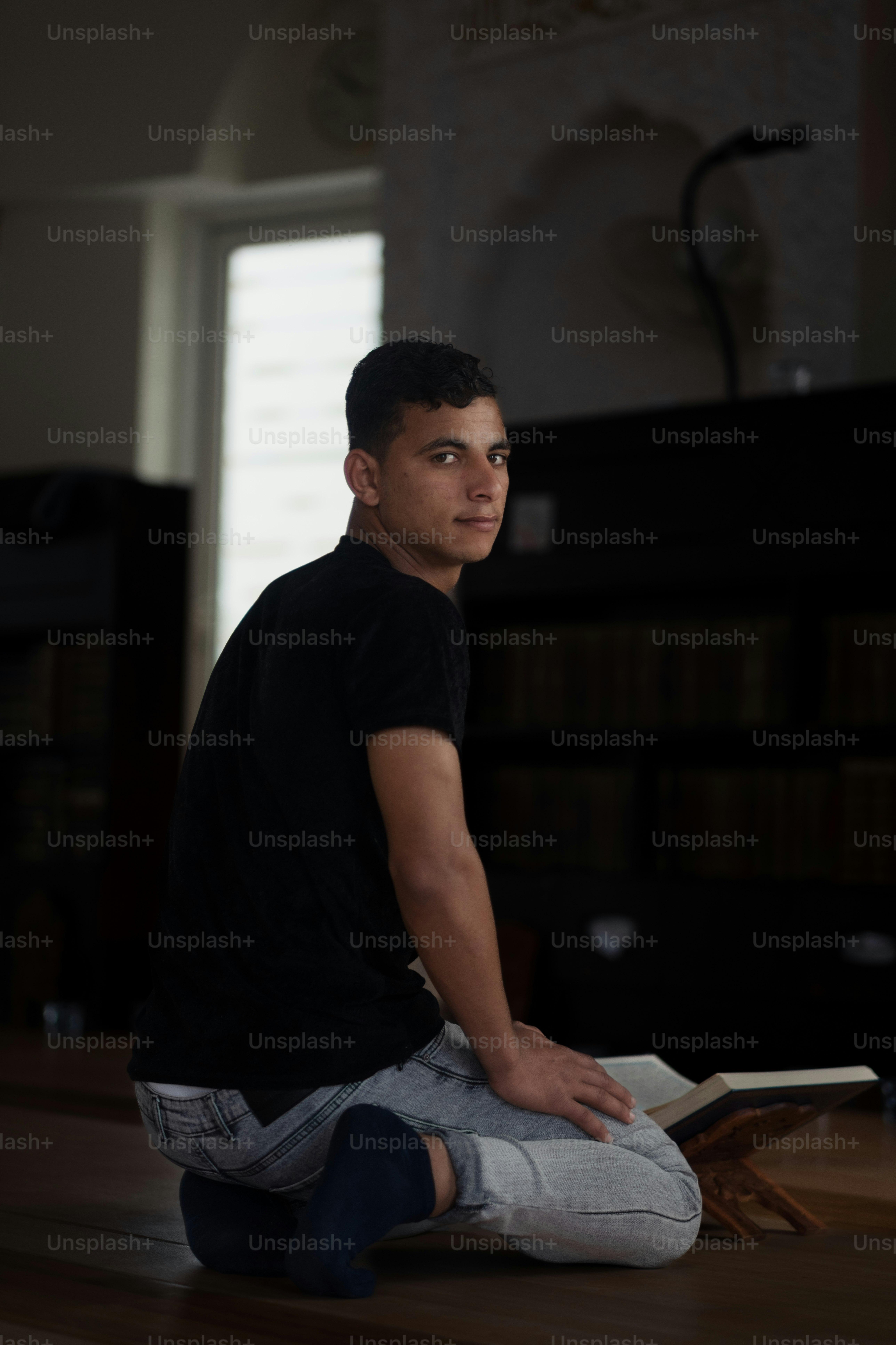 Un hombre sentado en el suelo leyendo un libro