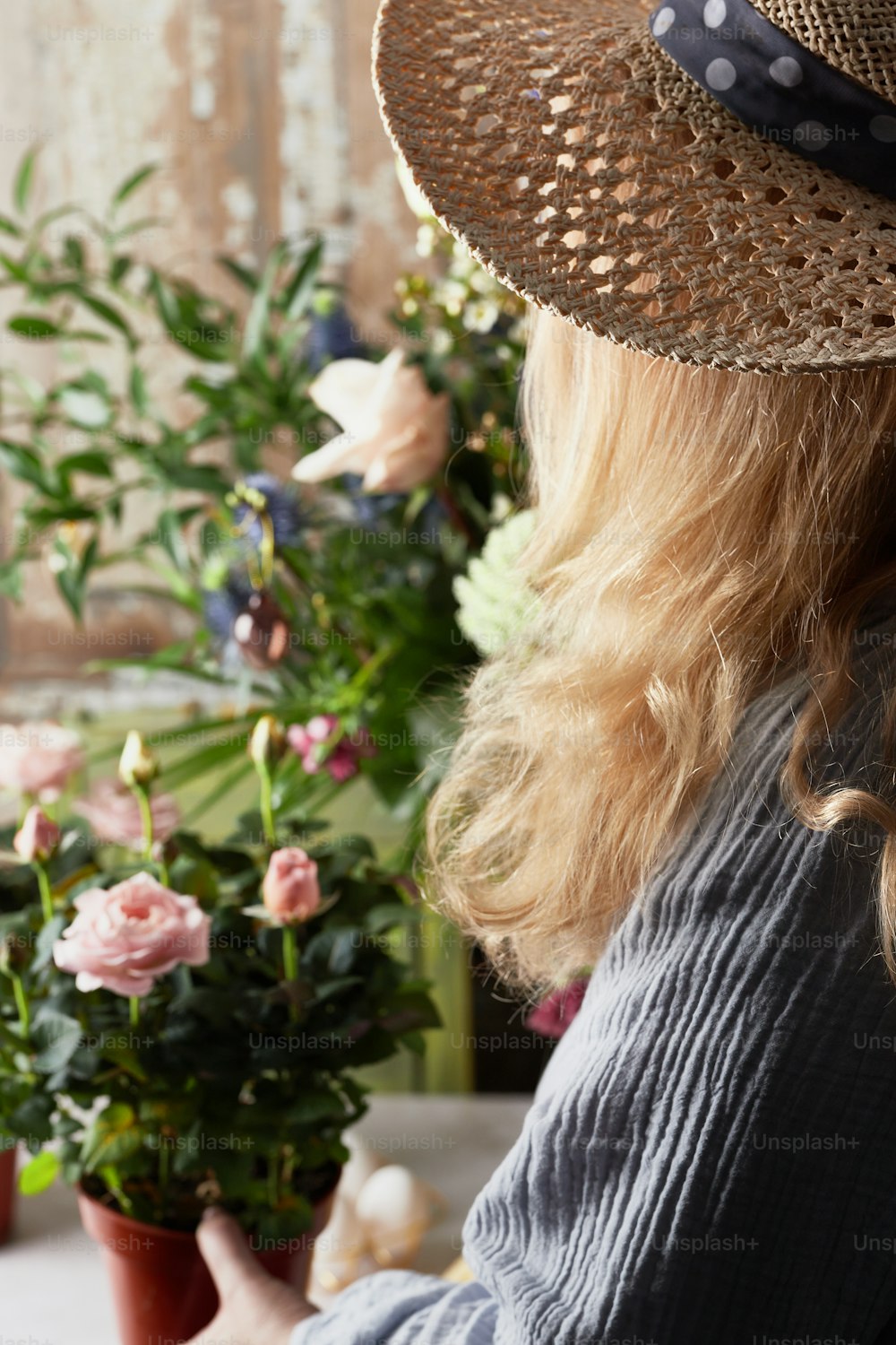 Una mujer con un sombrero mirando por una ventana