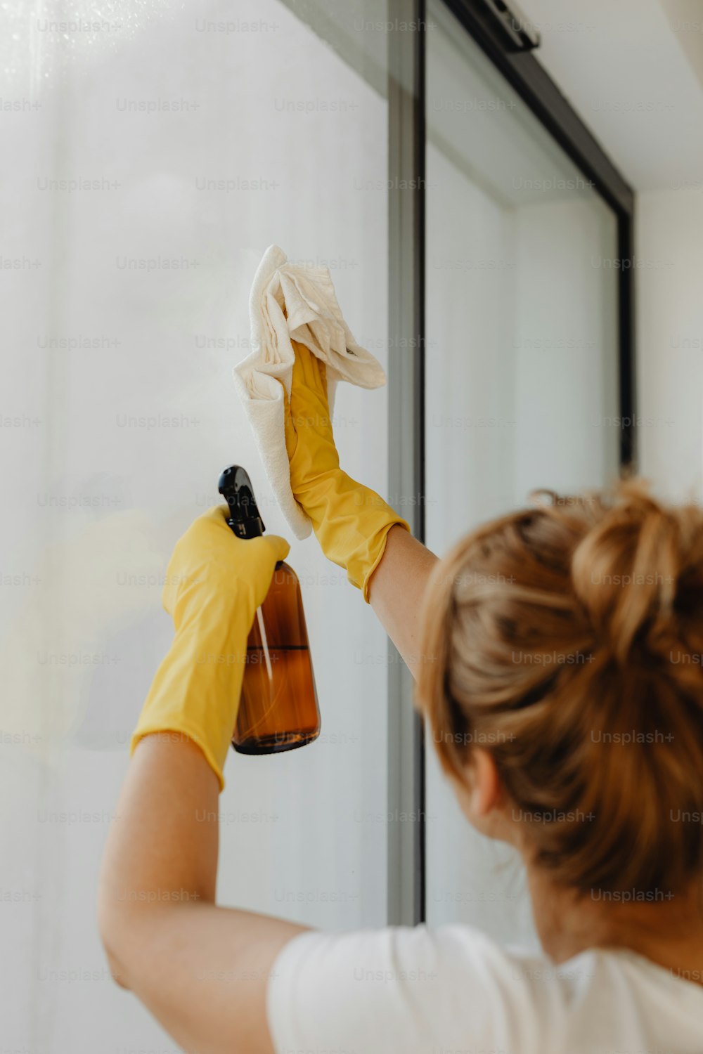 Una mujer con guantes amarillos está limpiando una ventana