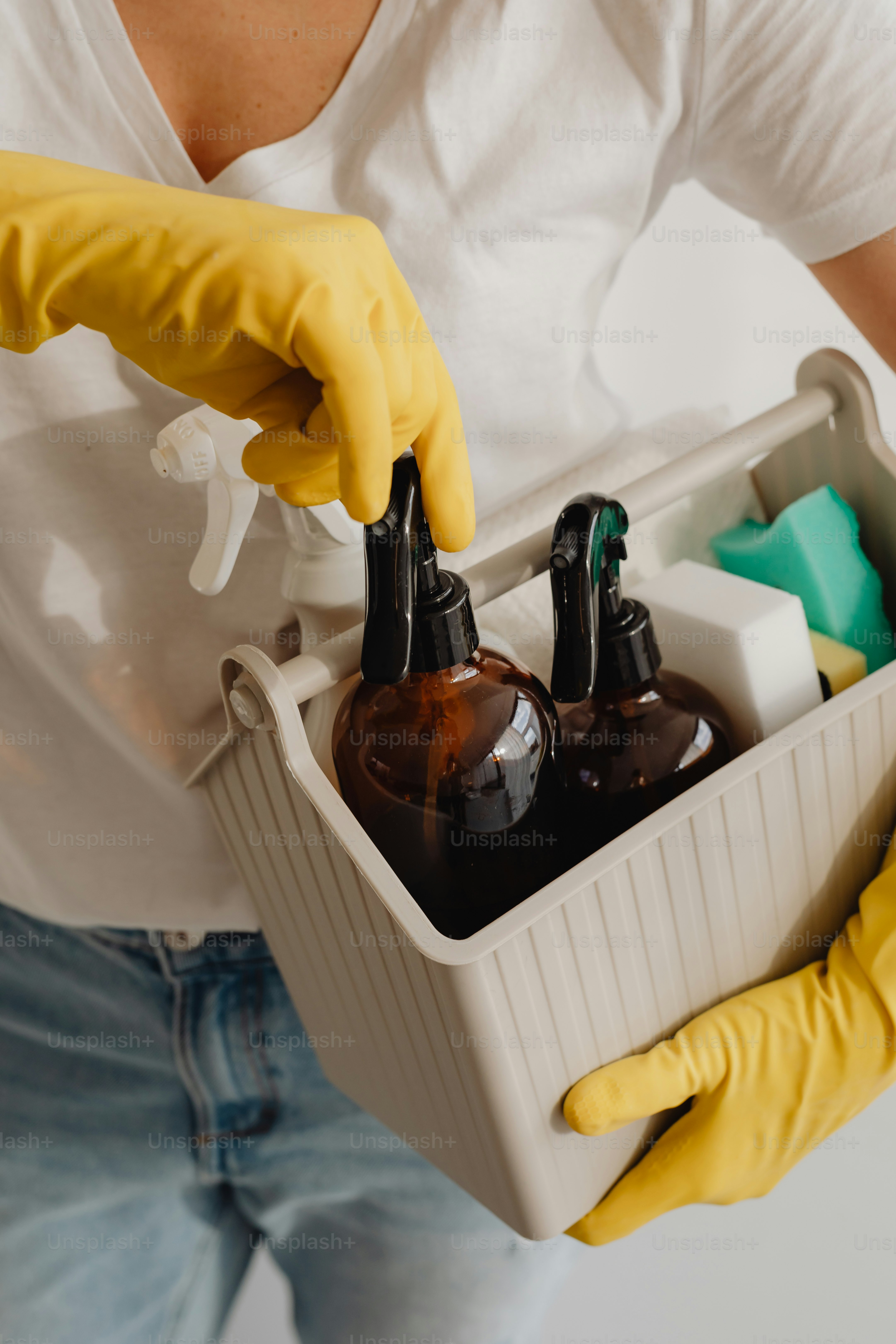 ボトルの入った容器を持っている黄色い手袋をはめた人
