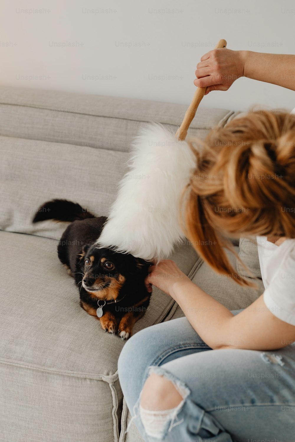 a woman sitting on a couch petting a dog