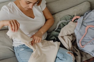 una donna seduta su un divano che guarda i vestiti