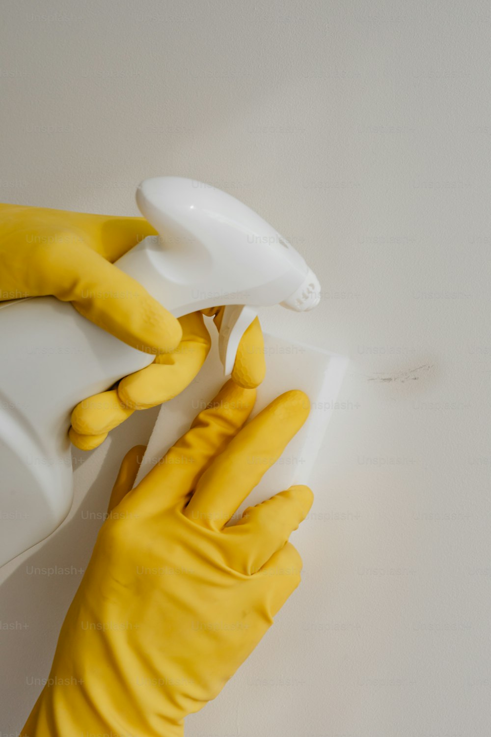 a pair of yellow gloves holding a spray bottle