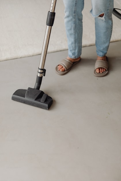 A professional janitor using an upright vacuum cleaner on a commercial floor in a modern facility