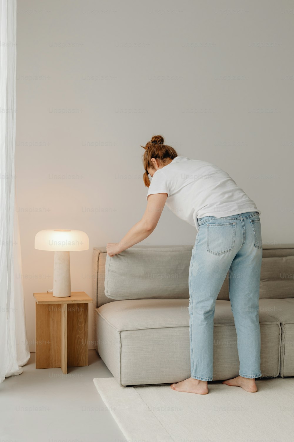 a woman in white shirt and jeans standing next to a couch