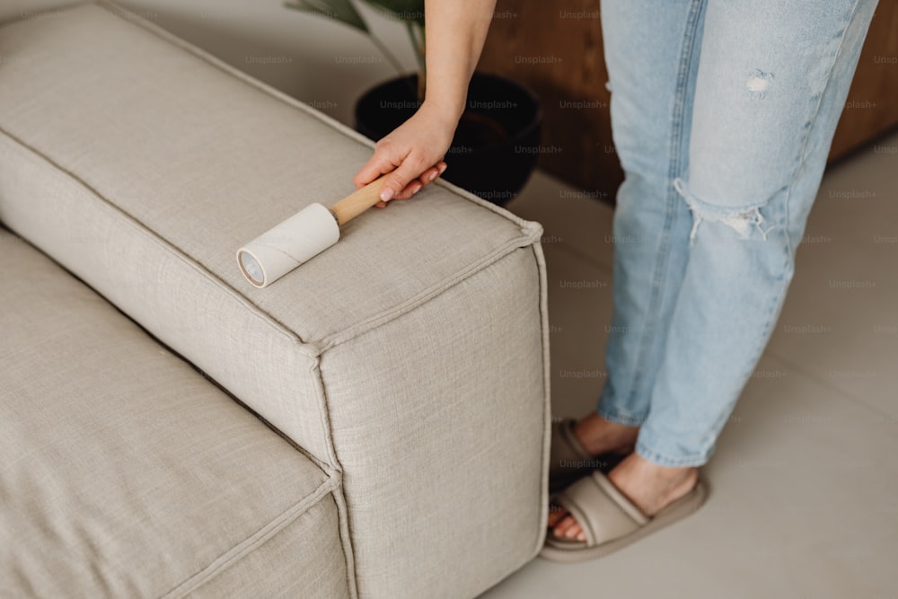 a woman is cleaning a couch with a roller
