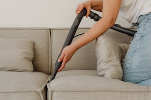 a woman using a vacuum to clean a couch