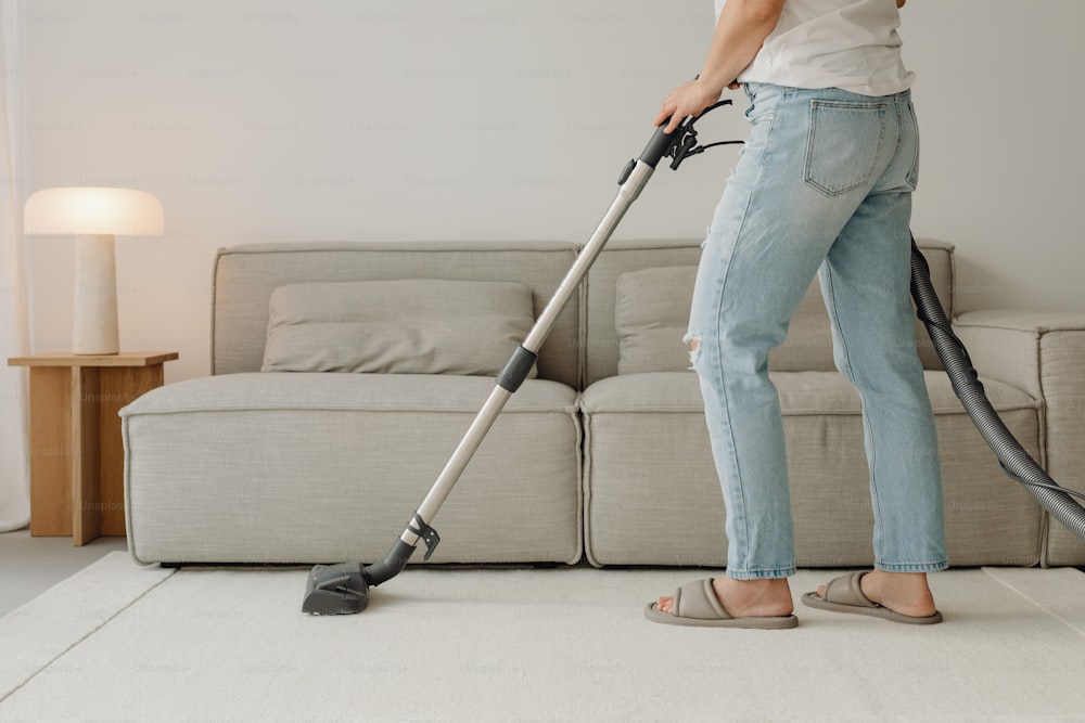 uma mulher que usa um aspirador para limpar uma sala de estar