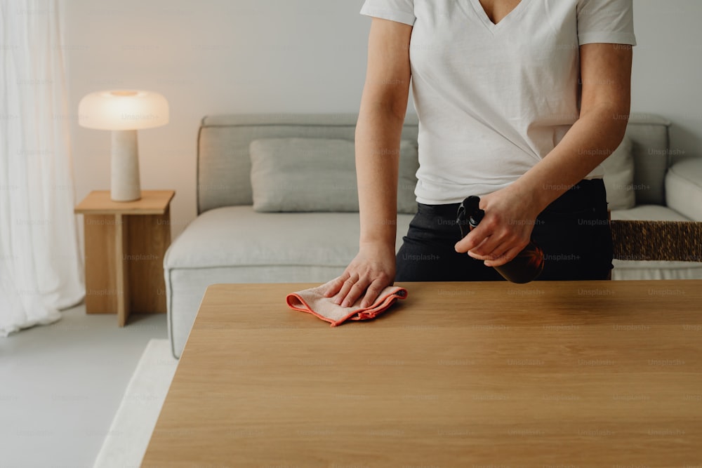 uma mulher que limpa uma mesa com um pano