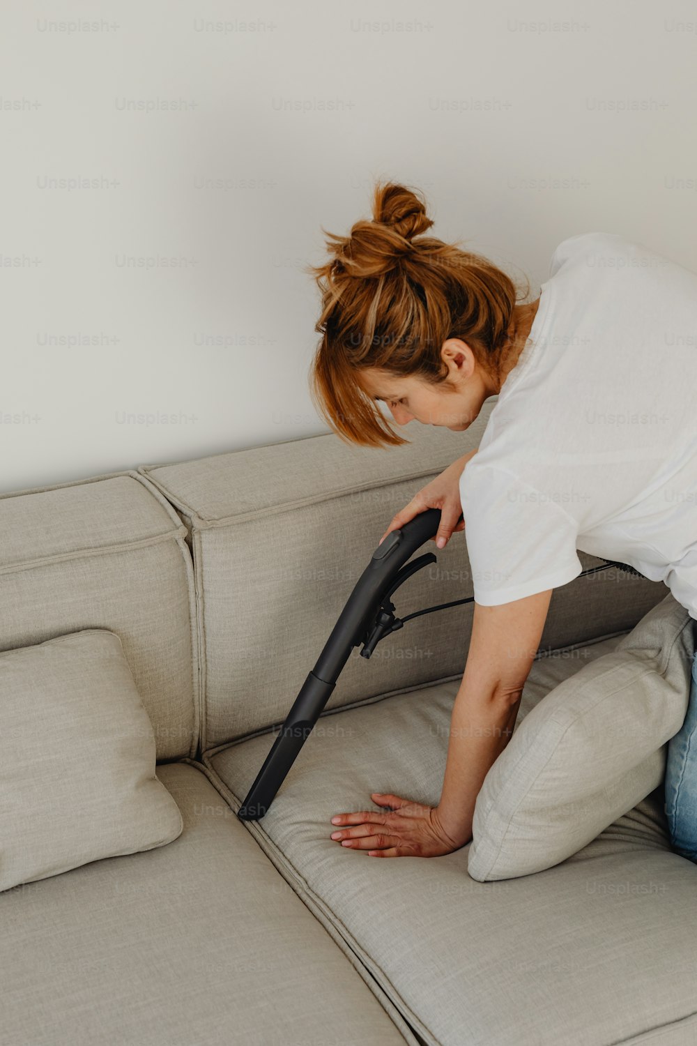 Une femme nettoie un canapé avec un aspirateur photo – Rangement