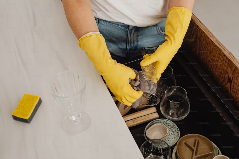 a person in yellow gloves is cleaning a table