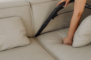 a person using a vacuum to clean a couch