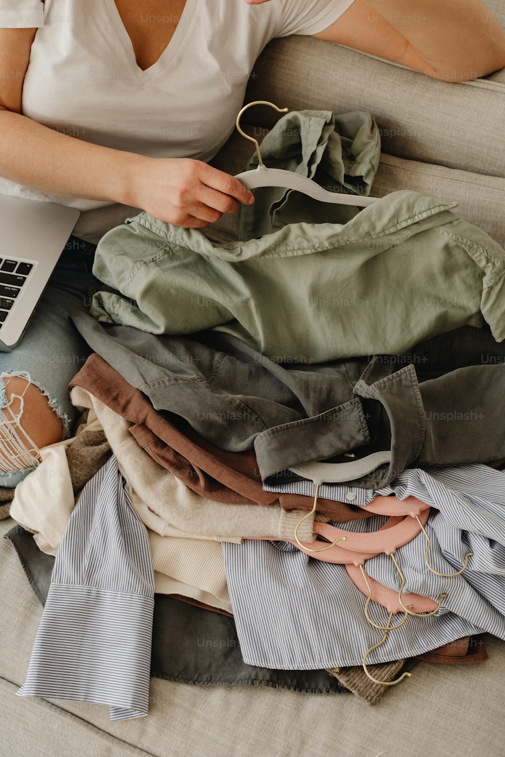 a woman sitting on a couch next to a pile of clothes