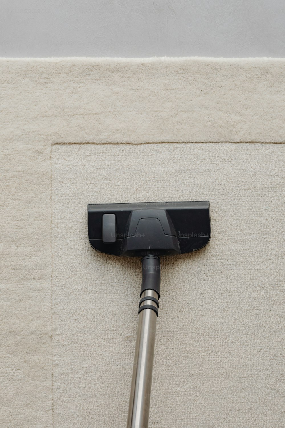 a black and silver floor sweeper on a beige carpet