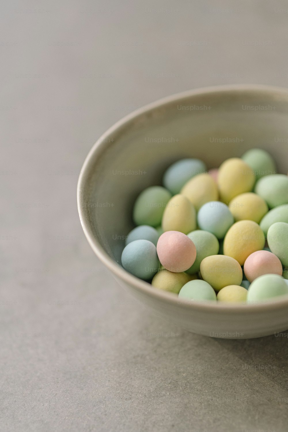 a white bowl filled with candy eggs on top of a table