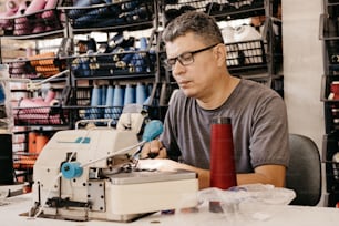a man sitting at a table with a sewing machine