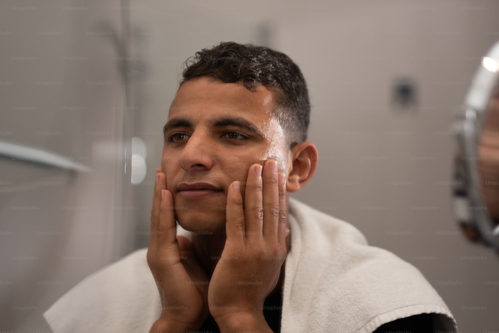 um homem está raspando o rosto na frente de um espelho