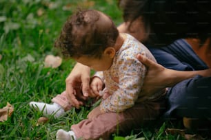 草の上で赤ん坊を膝に抱く女性