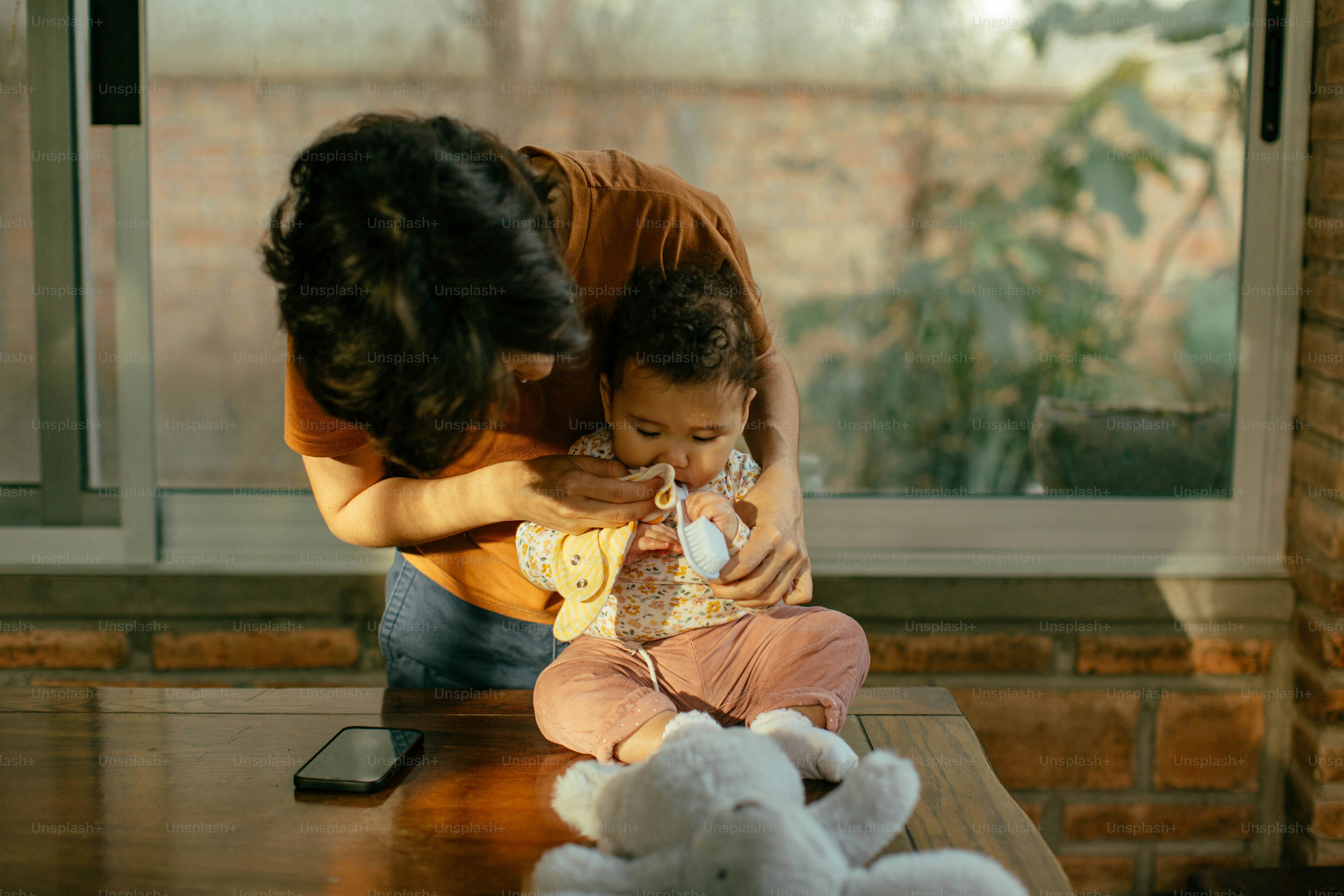 a woman holding a baby while sitting on a table