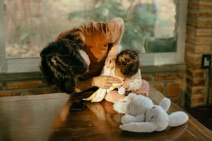 a woman holding a baby next to stuffed animals