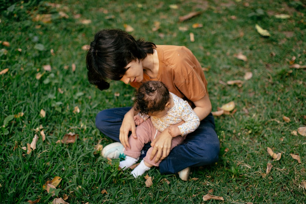 a woman holding a baby in a field of grass