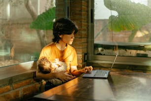a woman holding a baby using a laptop computer