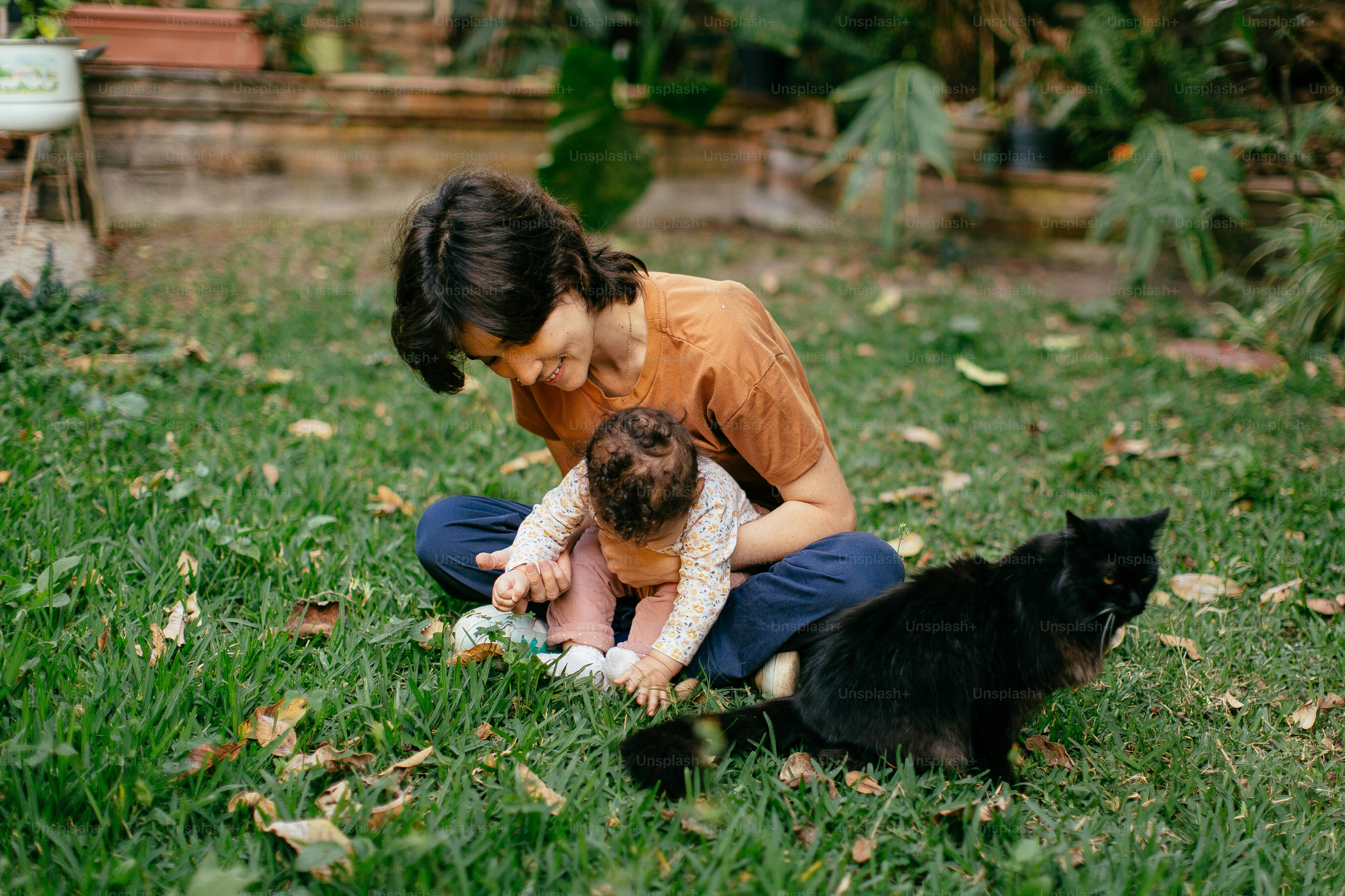 a woman holding a baby and two cats