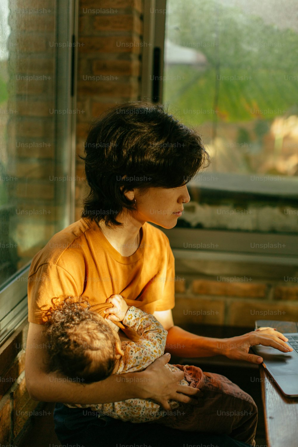 uma mulher que segura um bebê usando um computador portátil