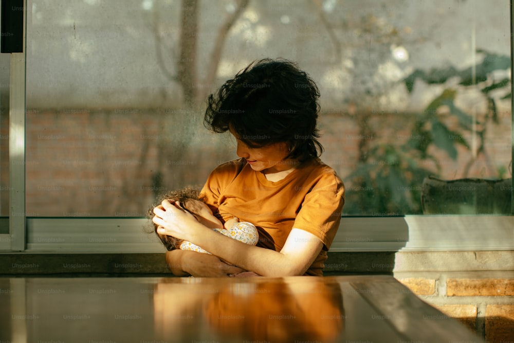 a young girl sitting at a table holding a bird