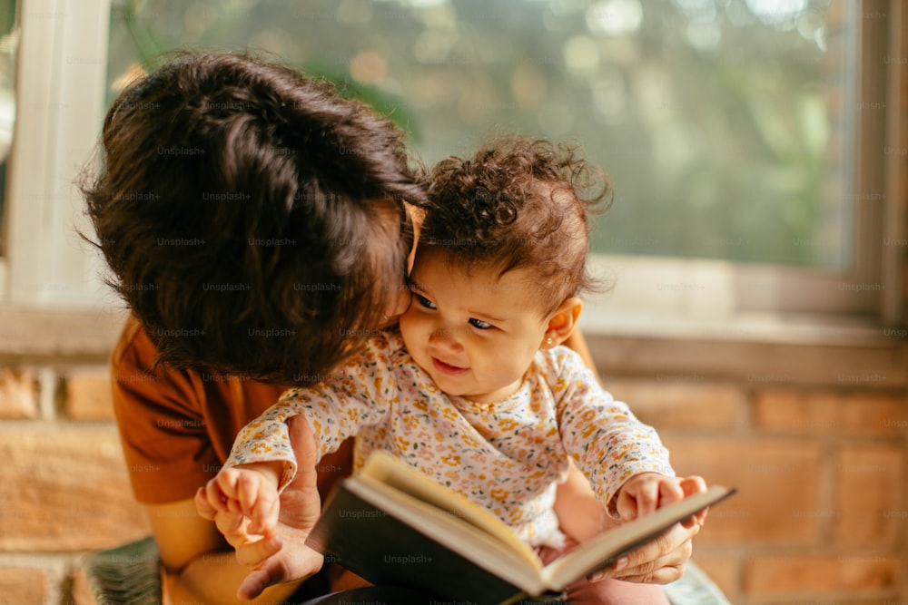 赤ちゃんに本を読む女性