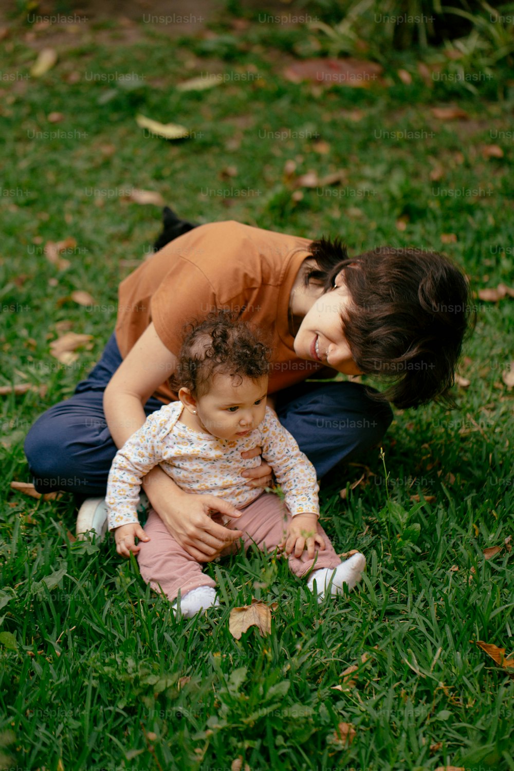 草の上で赤ん坊を膝に抱く女性