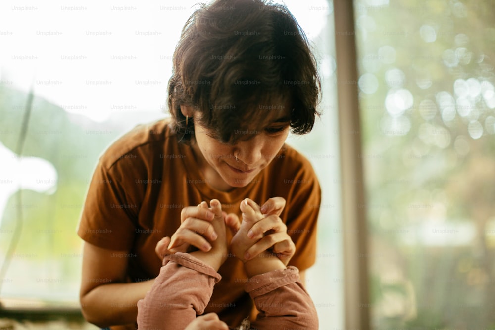 a woman holding a child's hands with both hands