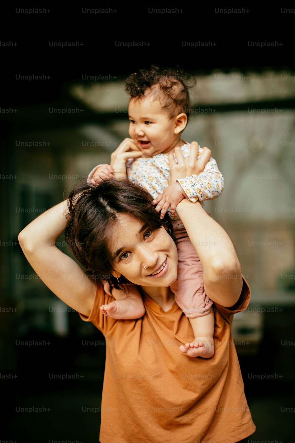 uma mulher segurando um bebê em seus ombros