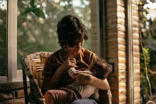 a woman sitting on a chair holding a baby